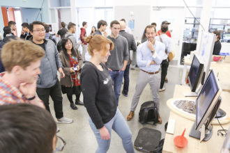 Group of students watch fellow student demonstrate Interaboard protoype with board and computer