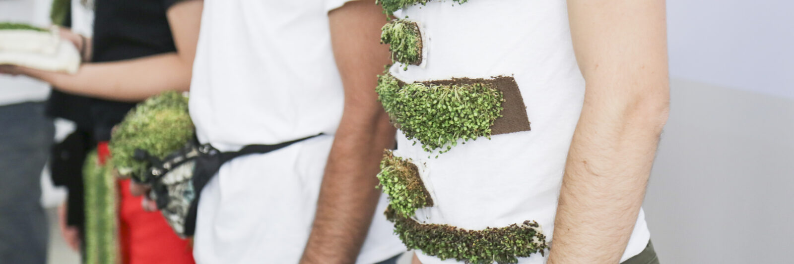 students demonstrate project wearing clothing items with plants growing on them
