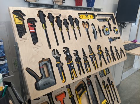 An organized hand-tool board with saws, pliers, wrenches, and screw drivers