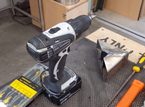 A Makita drill sits on a table with several hand tools