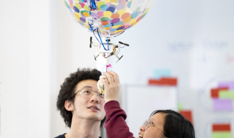 Photo of two students and a blimp drone