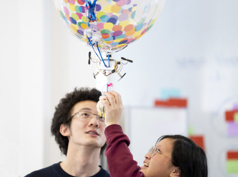 Photo of two students and a blimp drone